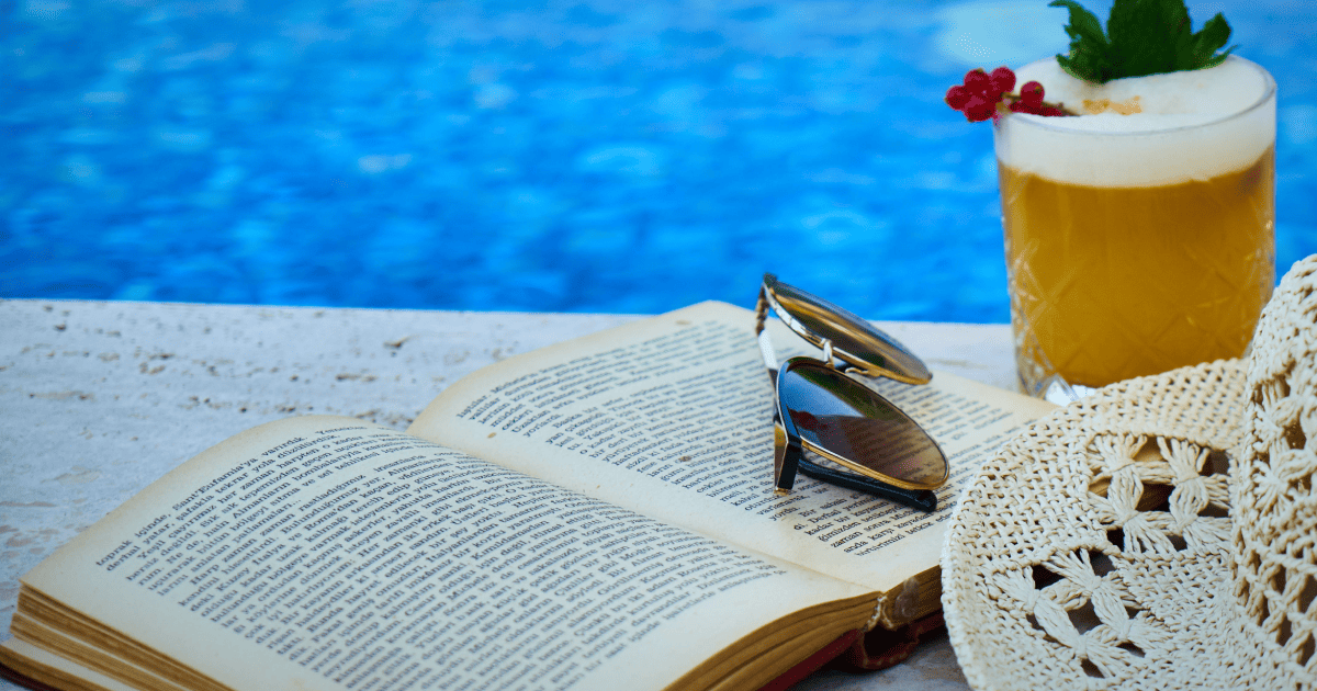book, sunglasses, and a drink by the pool.