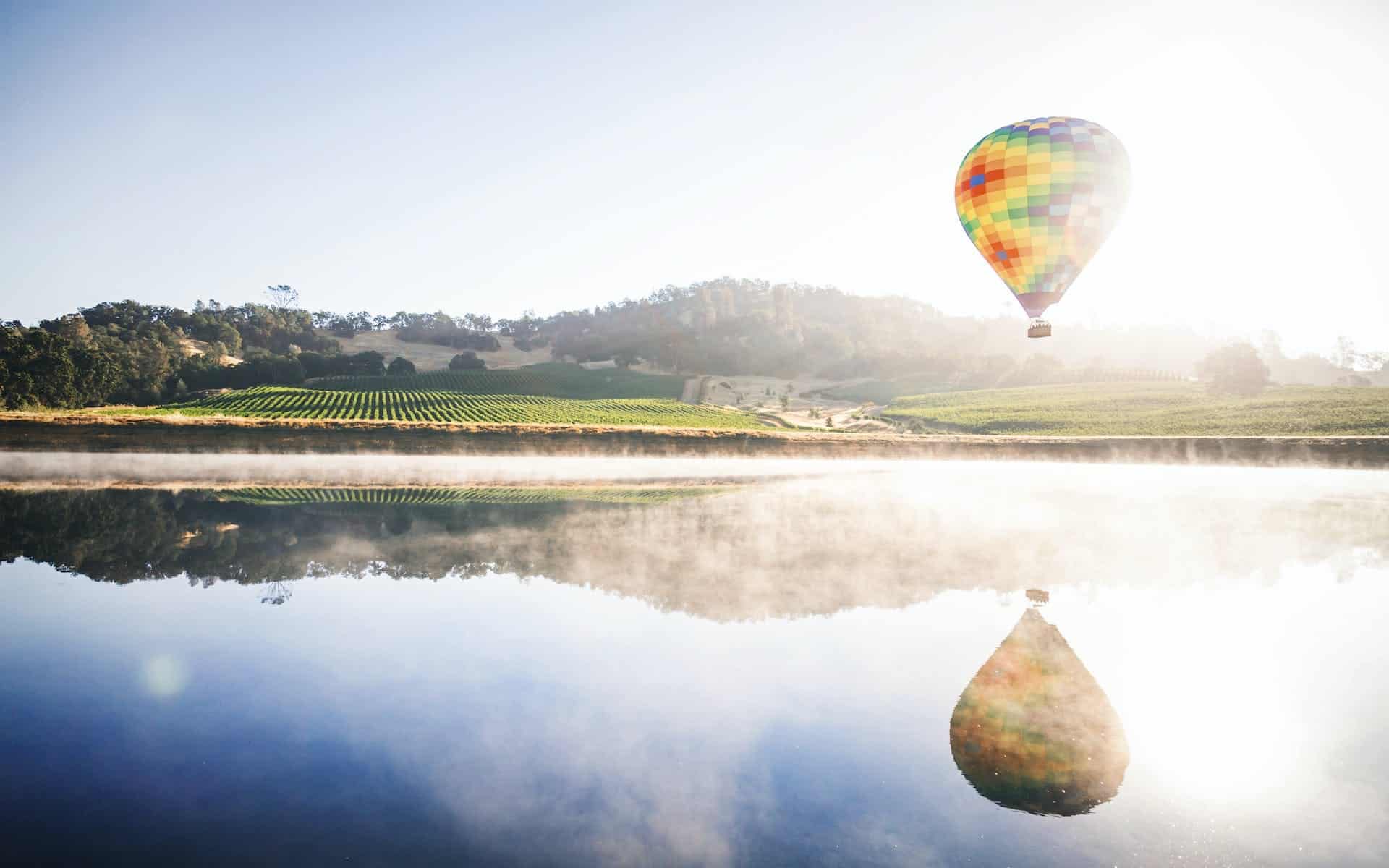 Hot air balloon flying over wineries in Napa Valley, CA.