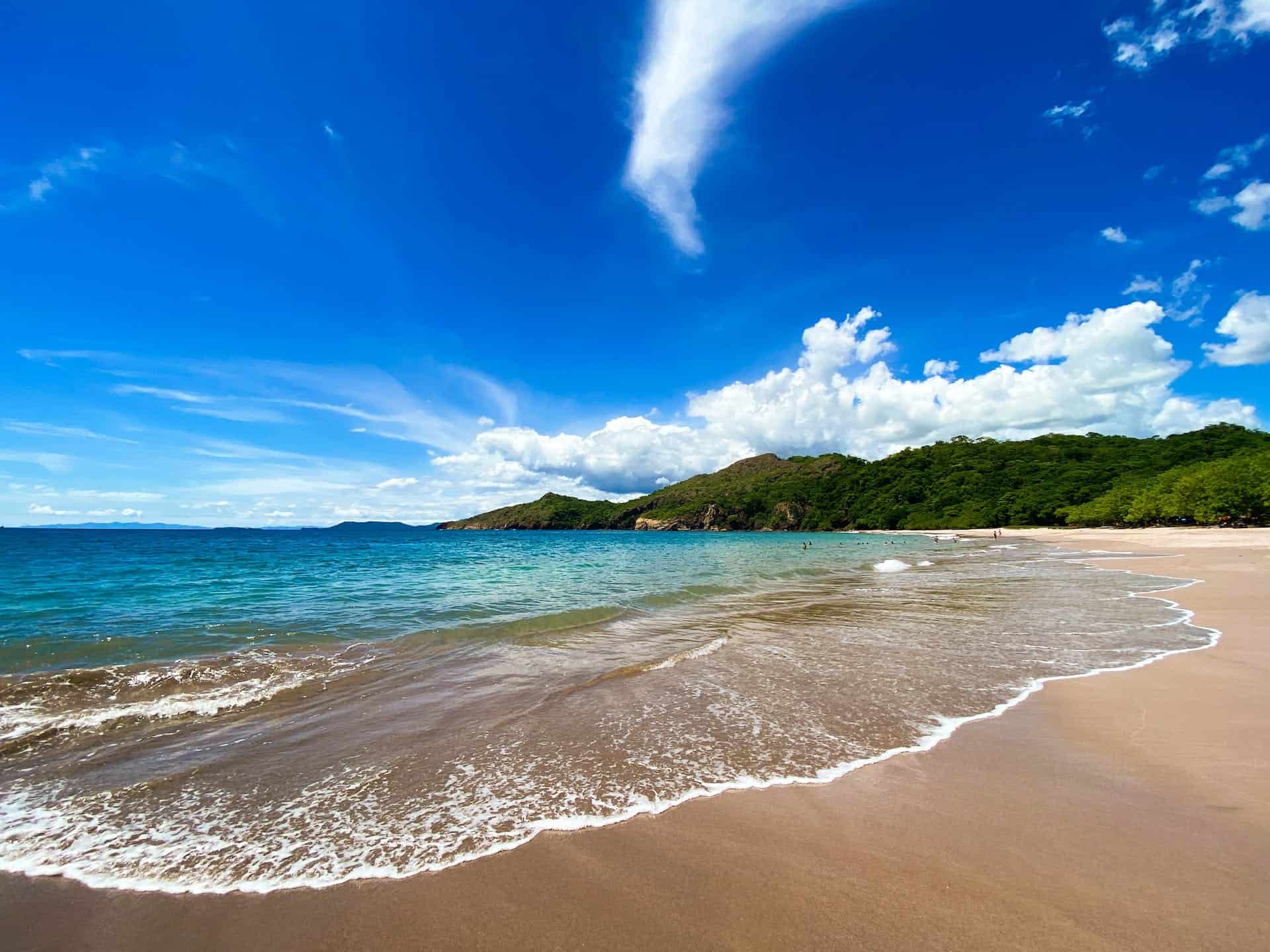 Beach in Costa Rica with mountains in the background on a clear day.