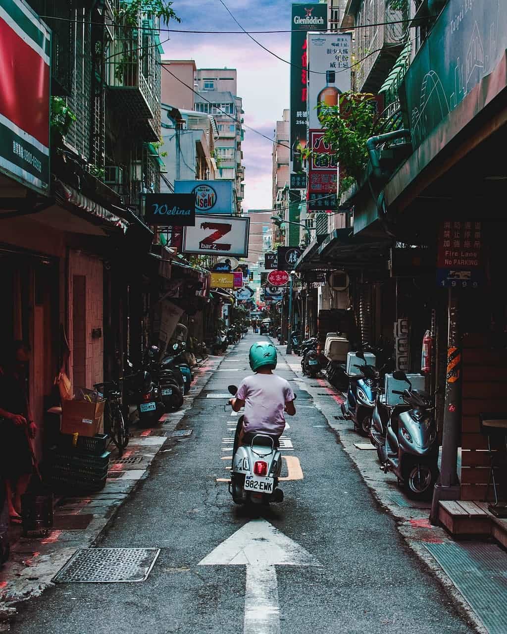 Man on moped through a narrow alley