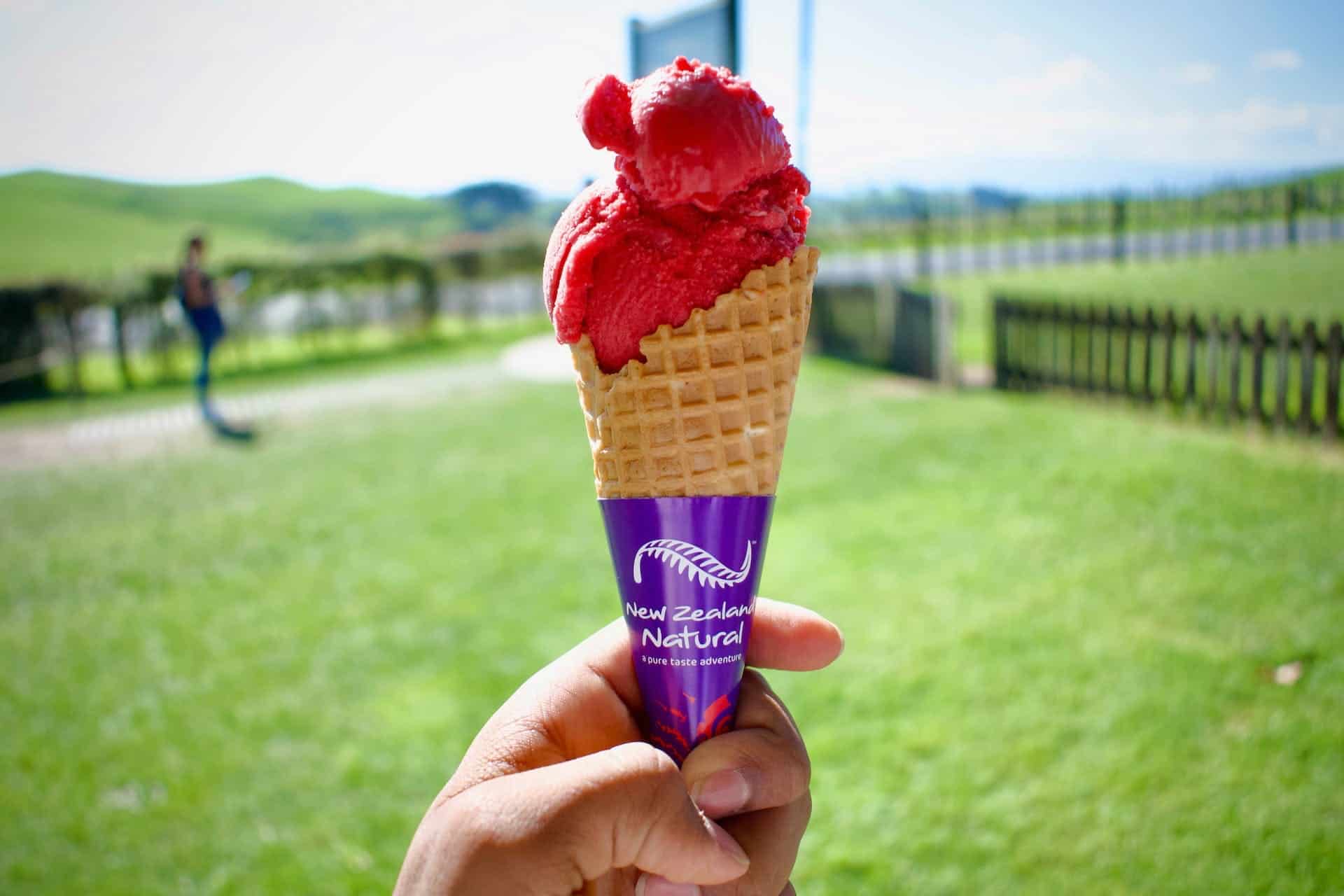 Someone holding up an ice cream cone on a farm in New Zealand with a label on the ice cream that says 