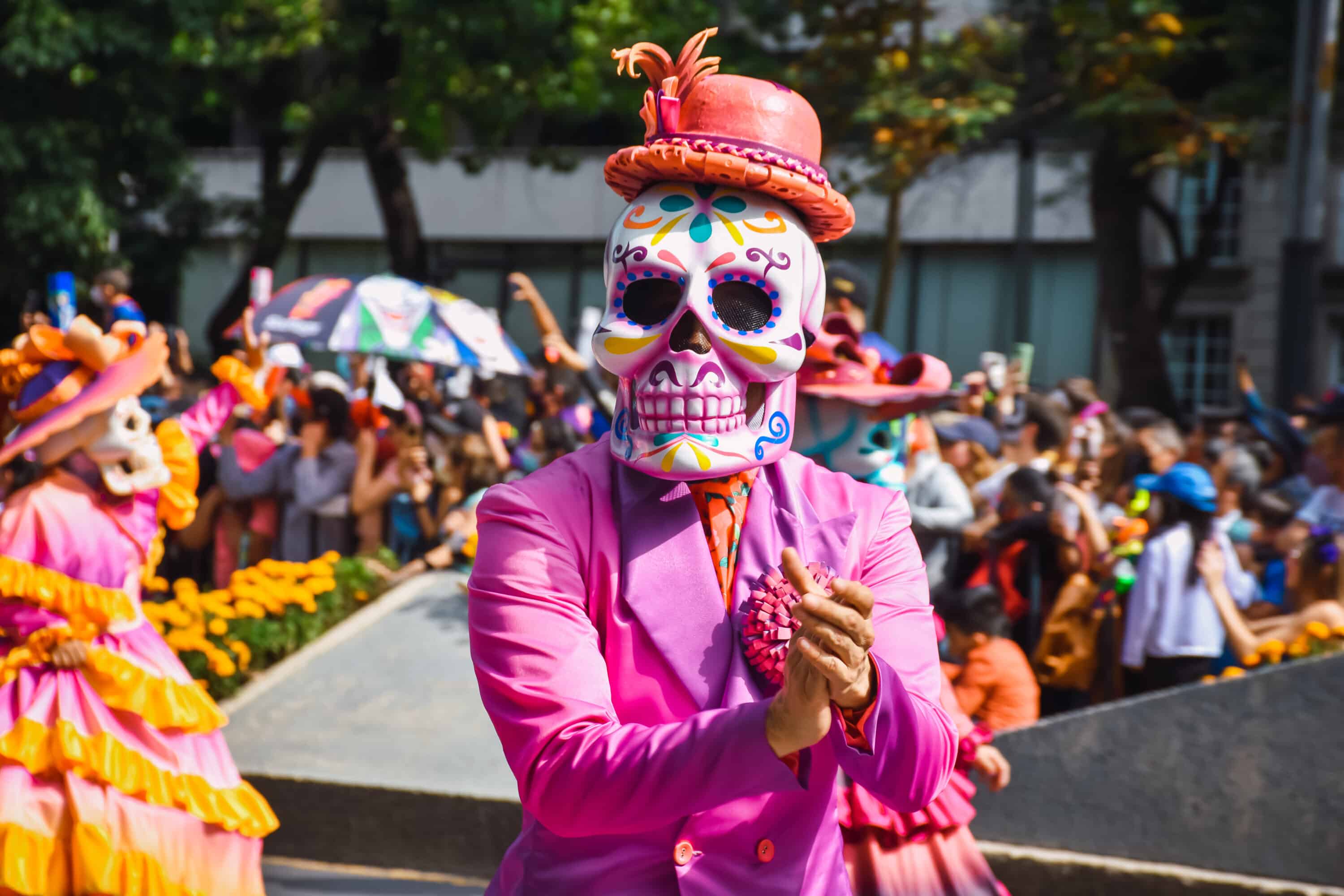 a person wearing a mask in a parade during Day of the Dead