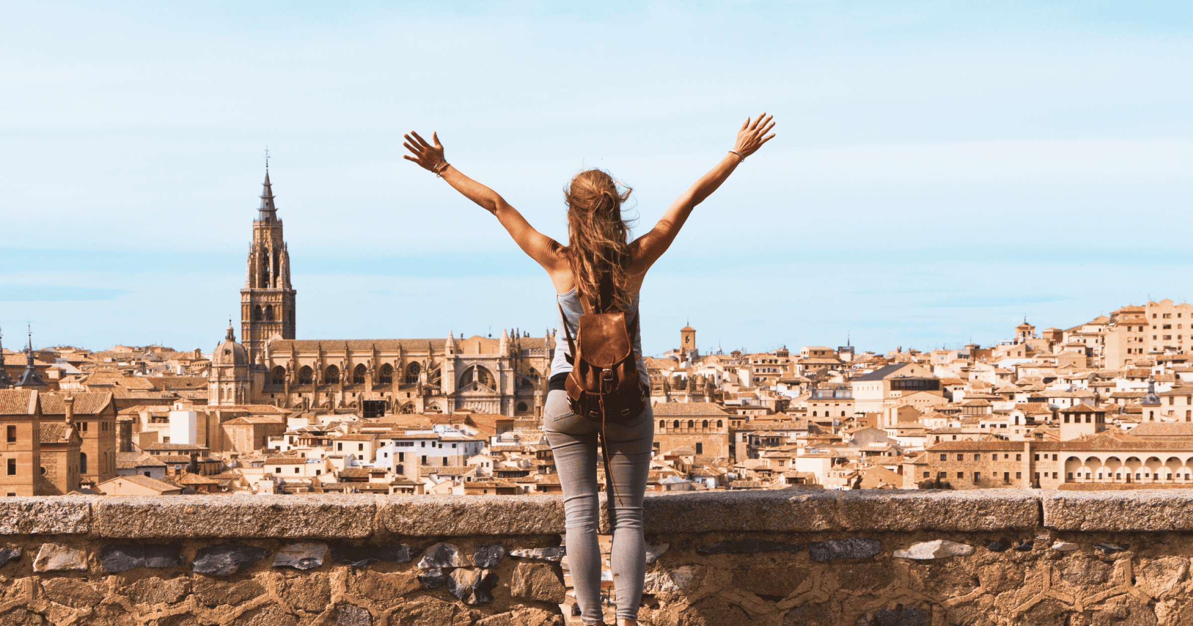 Woman with her hands up overlooking Spain from a balcony