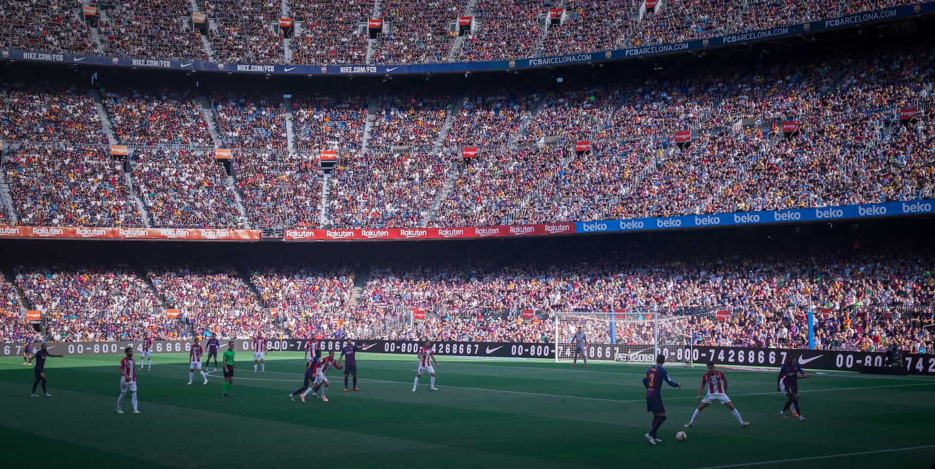 Large crowd of people sitting in the stands while soccer players play on the field at a soccer game in Spain.