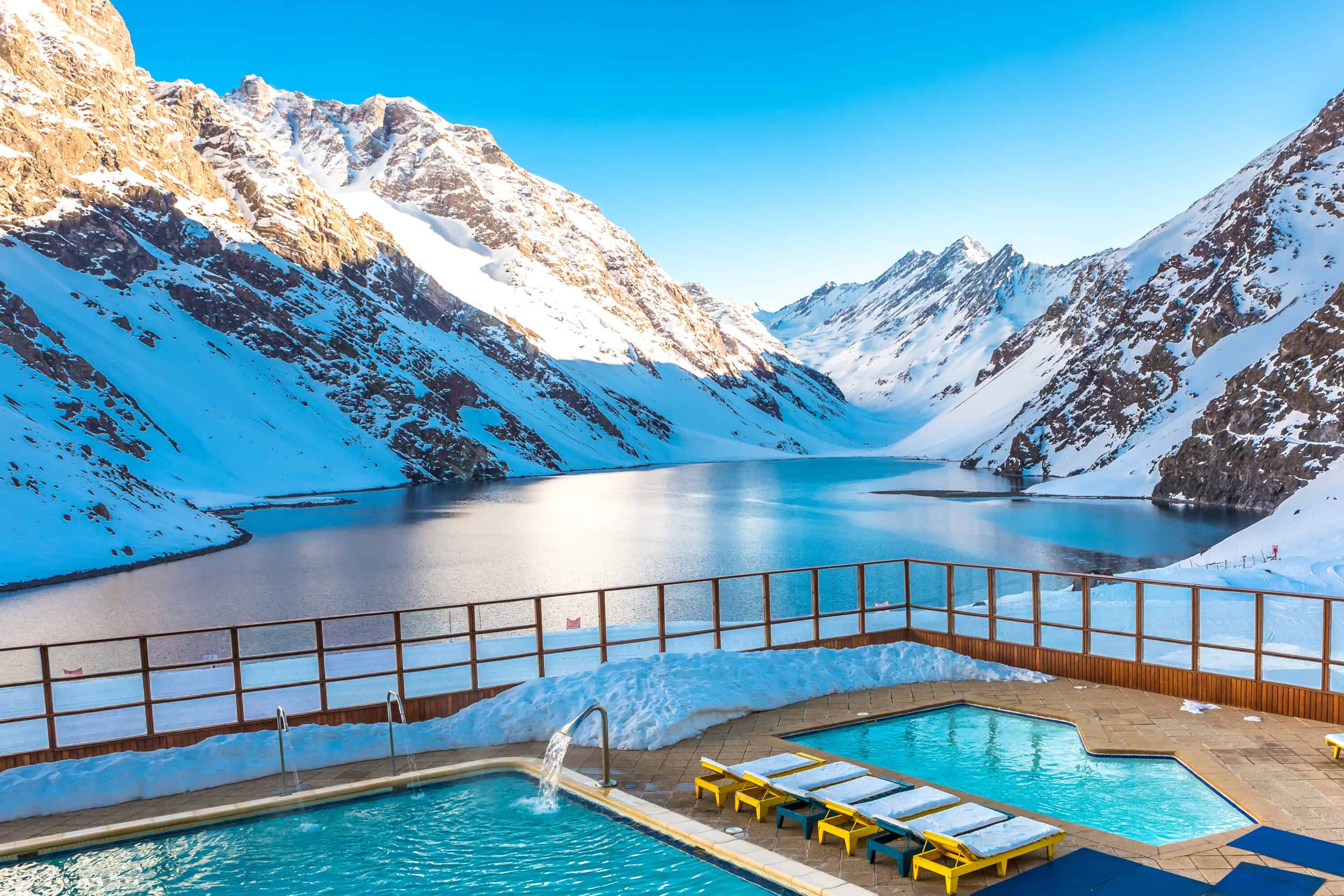 A pool right by a snowy mountain in Chile on a sunny day.