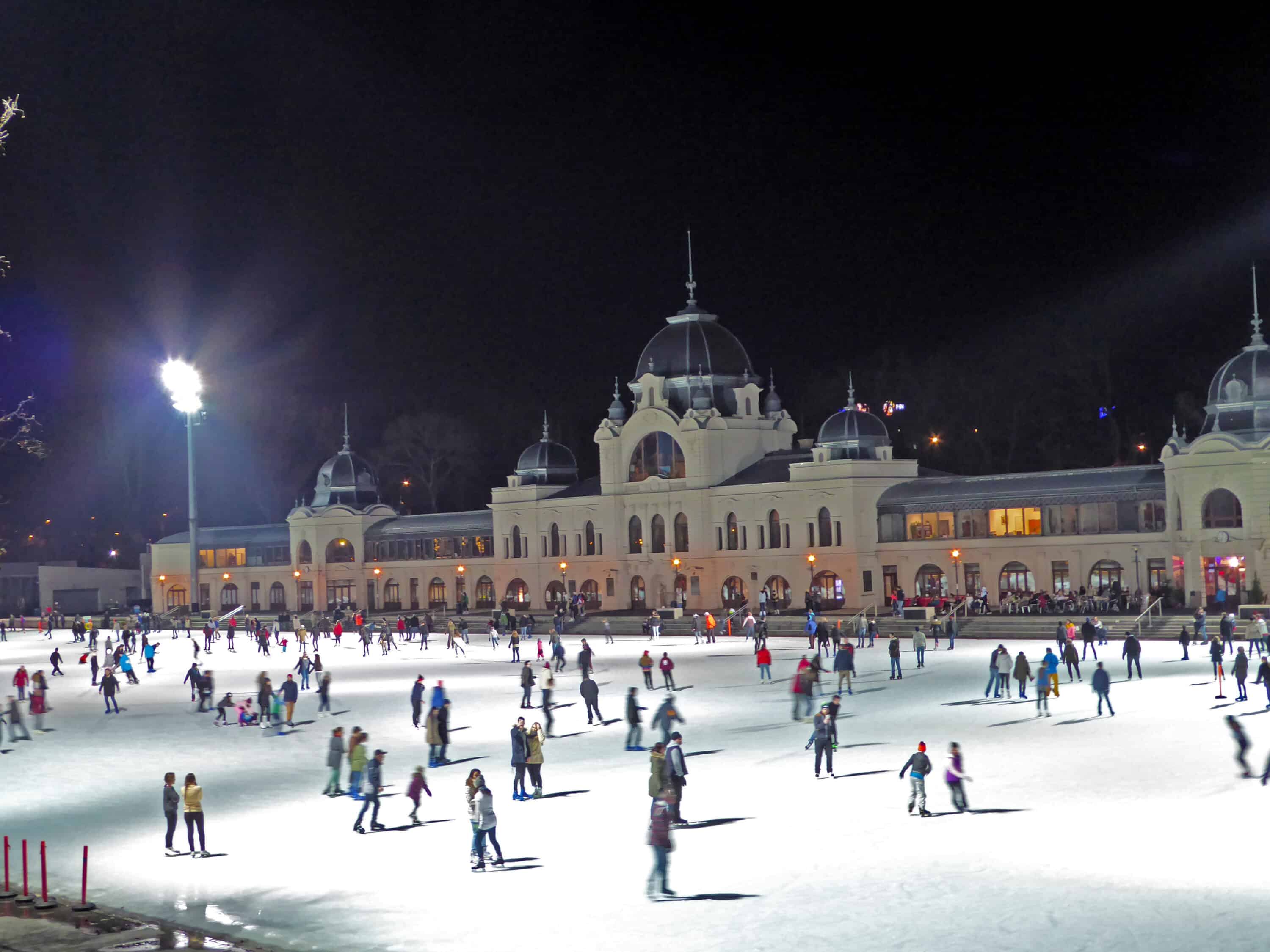 People ice skating at night at the City Park Ice Rink in Budapest, Hungary.