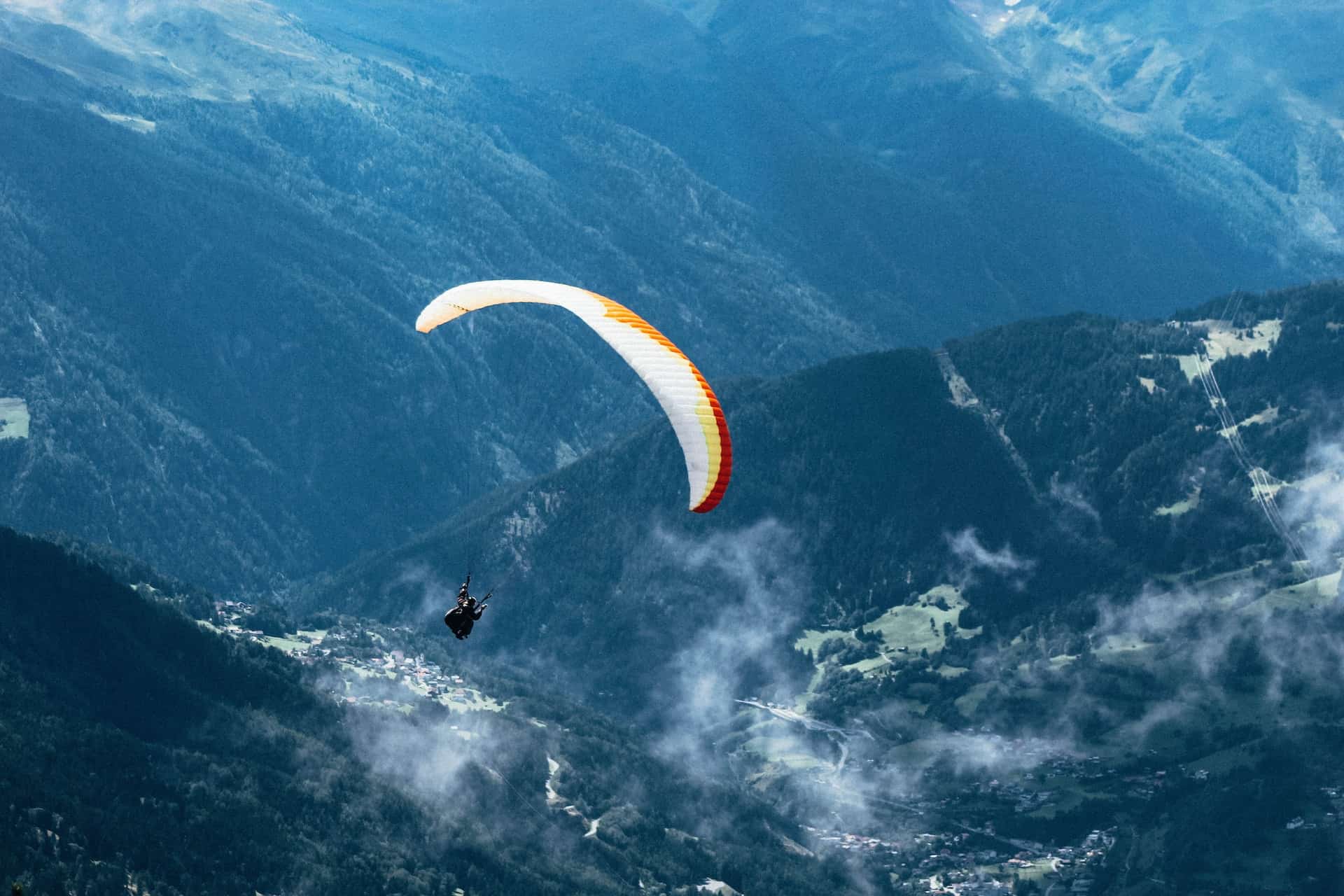 person-paragliding-over-mountain-ranges