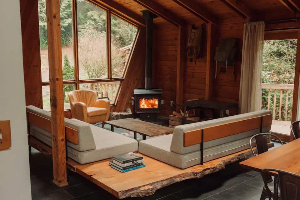 The interior of Canyon Creek Cabins #1 in Washington State featuring a wood burning fireplace and wood panels on the wall. 