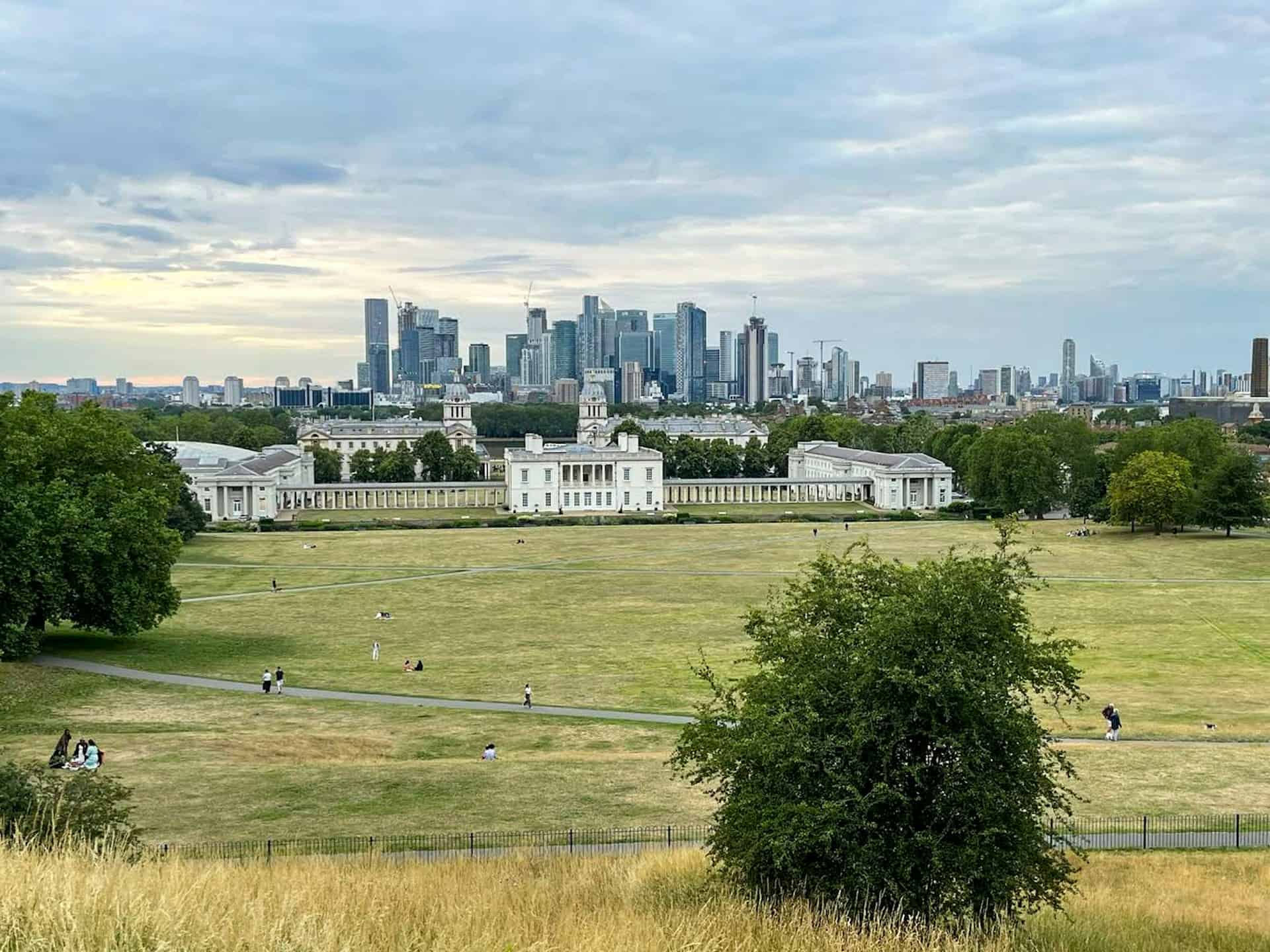 a view of a city skyline from a grassy field Greenwich park, UK