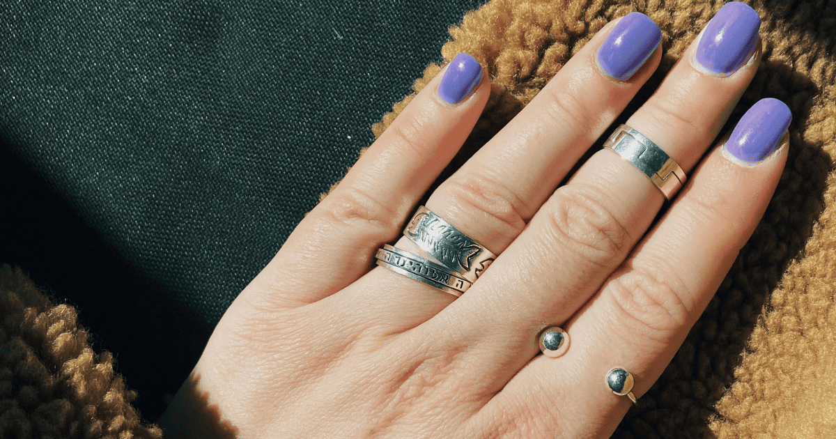 girls hand with purple nail polish and silver rings