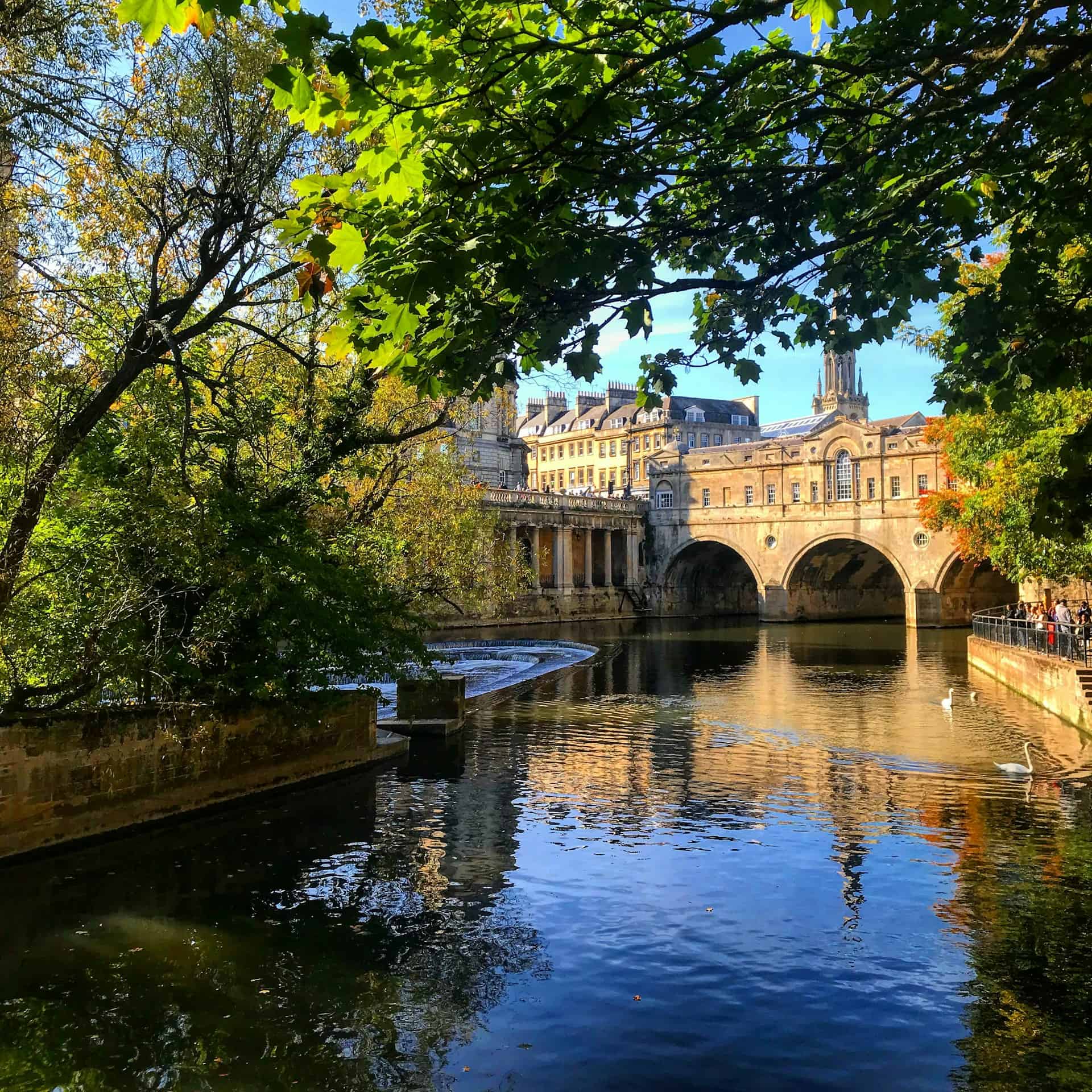 View of the water in Bath, England with a gothic building in the background. 