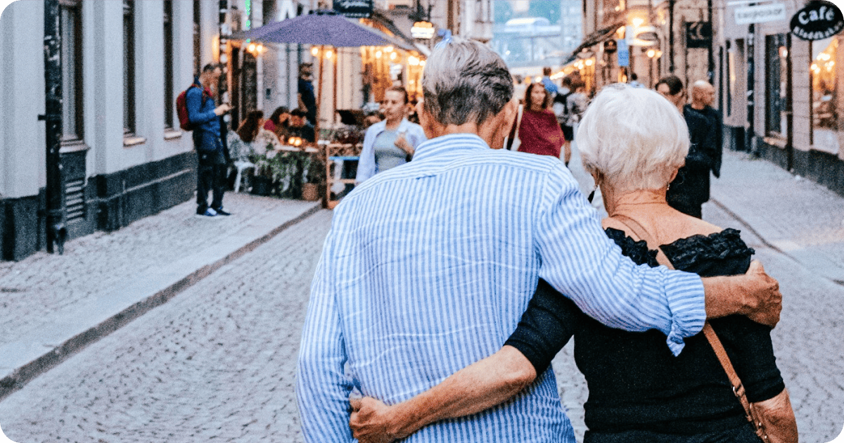Older couple walking arm in arm in a city on a trip