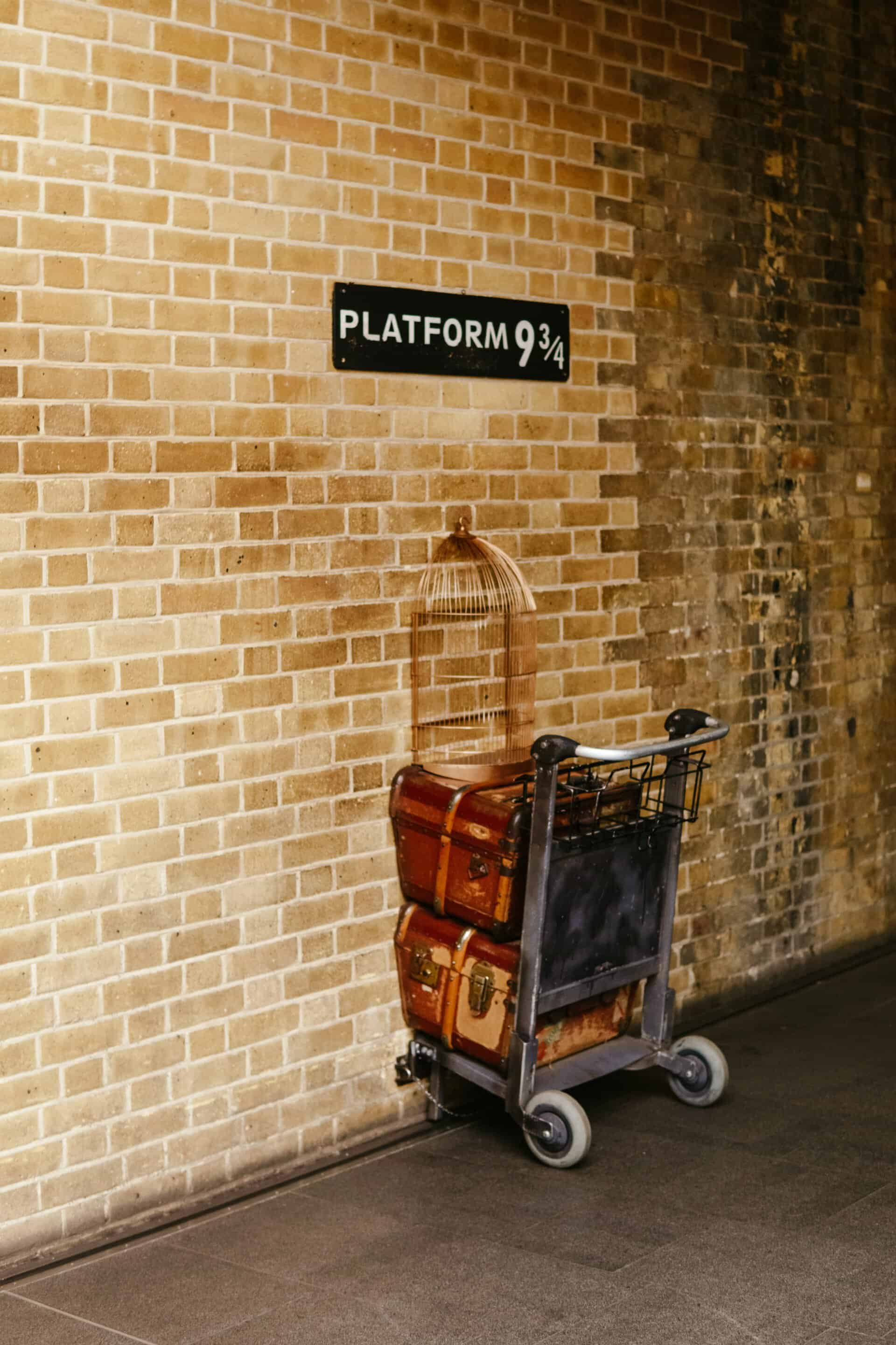 A sign that says "Platform 9 3/4" with a cart going into the wall from the Harry Potter movies at King's Cross station in London, England. 