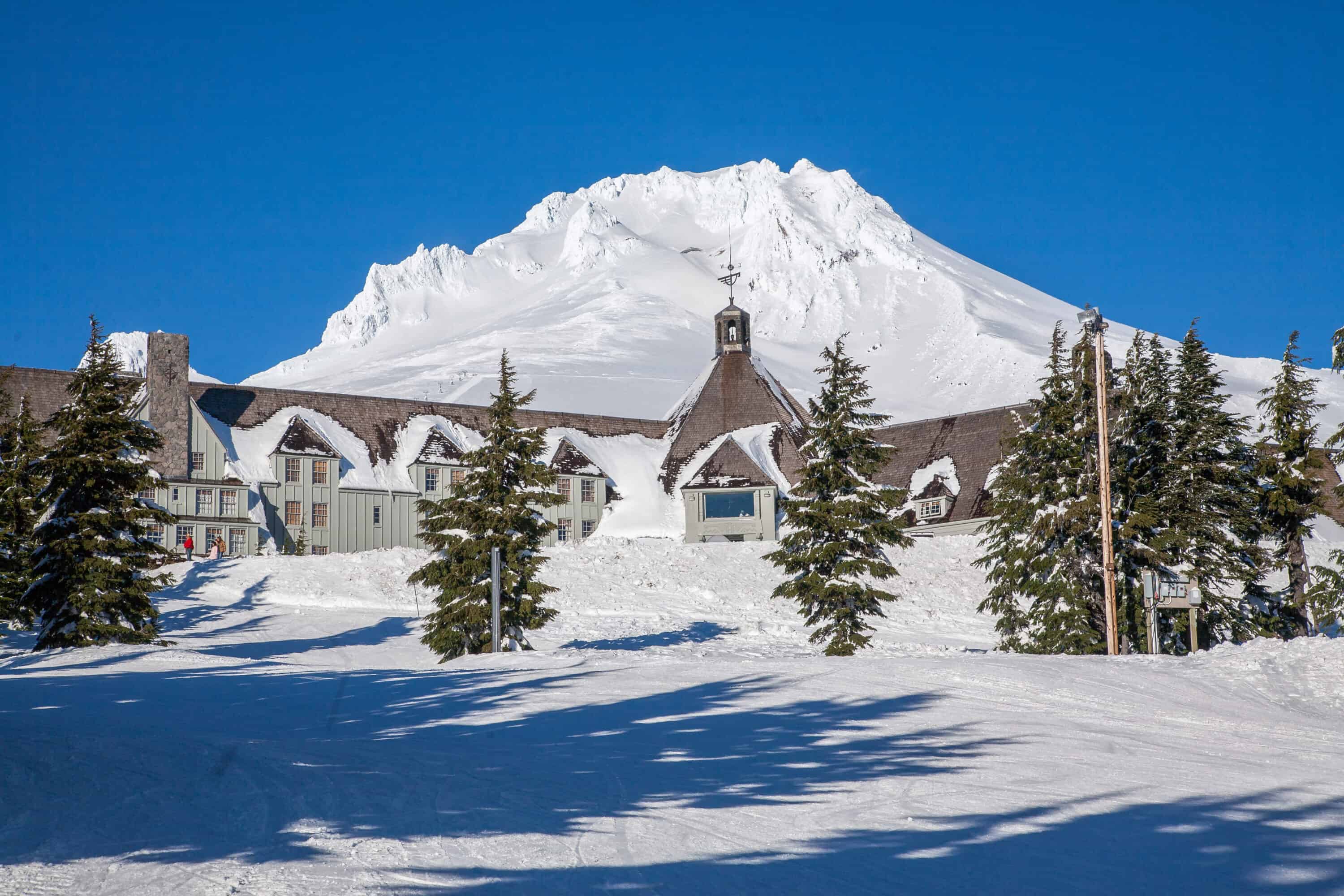 A snowy Timberline Lodge in Oregon where the Shining was filmed with a snowy mountain in the background. 