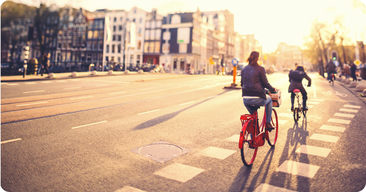 2 bikers in a bike lane in a city. One on a bright red bike.