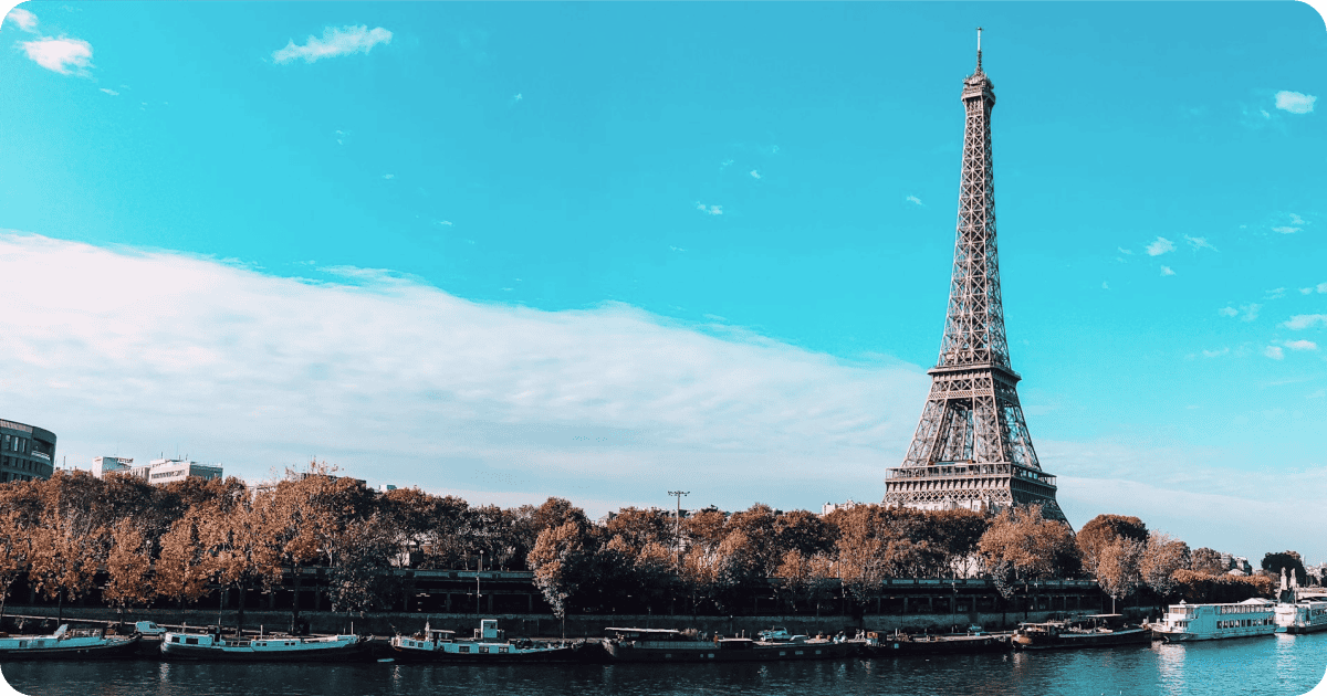 View of Eiffel Tower from the Siene river with blue skys in the background.